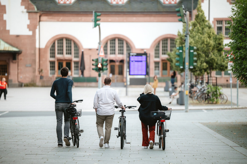 Drei Personen schieben ihre Fahrräder zum Bahnhof. Das Fachzentrum Nachhaltige Mobilitätsplanung Hessen unterstützt Kommunen beim Ausbau der nachhaltigen Mobilität